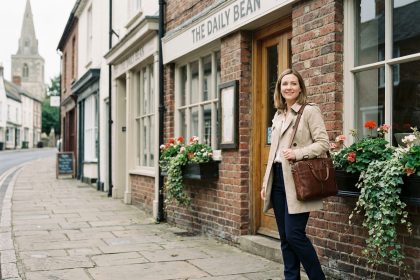 Femme en trench et pantalon business devant un café charmant